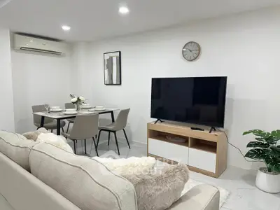 Modern living room with dining area, featuring sleek furniture and a wall-mounted TV.