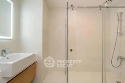Modern bathroom with sleek shower enclosure and stylish sink in a contemporary home.