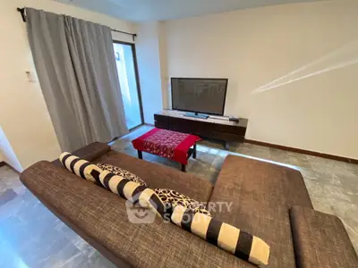 Spacious living room with modern sofa and flat-screen TV, perfect for relaxation and entertainment.