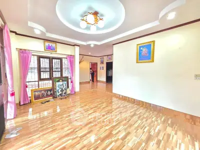 Spacious living room with elegant ceiling design and wooden flooring, perfect for family gatherings.