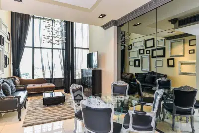 Luxurious living room with high ceilings, elegant decor, and large windows offering natural light.