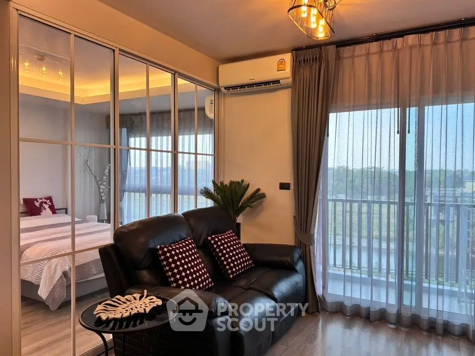Modern living room with leather sofa and glass partition to bedroom, featuring scenic balcony view.