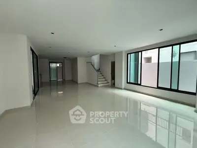 Spacious modern living room with large windows and sleek tile flooring in a contemporary home.