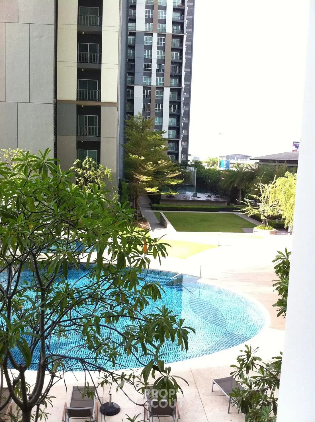 Luxurious residential complex with a stunning pool and lush garden view.