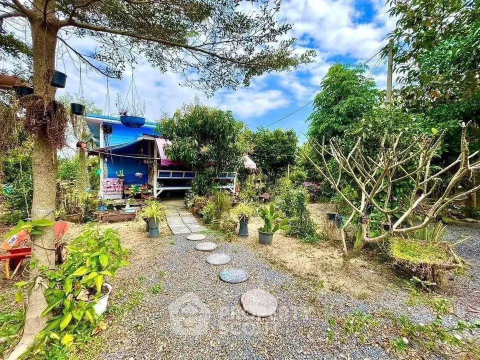Charming garden view with lush greenery and quaint blue house, perfect for nature lovers seeking tranquility.