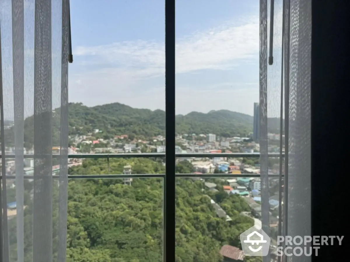 Stunning panoramic view from high-rise apartment window with lush greenery and cityscape.