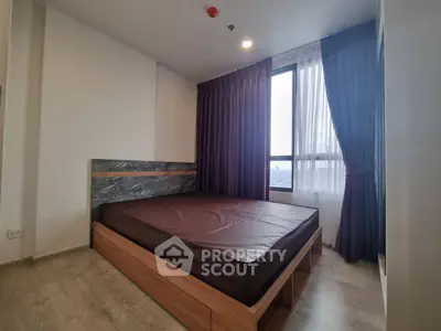 Modern bedroom with large window and stylish curtains in a high-rise apartment.