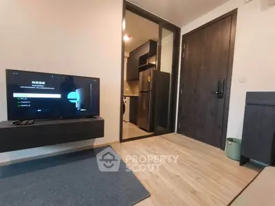 Modern apartment interior with sleek kitchen and cozy living area featuring a flat-screen TV.