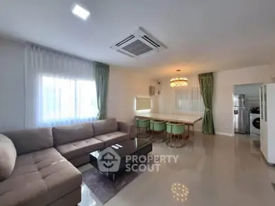 Spacious modern living room with elegant dining area and sleek kitchen appliances.