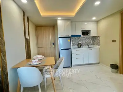 Modern kitchen with dining area, sleek white cabinets, and stylish lighting