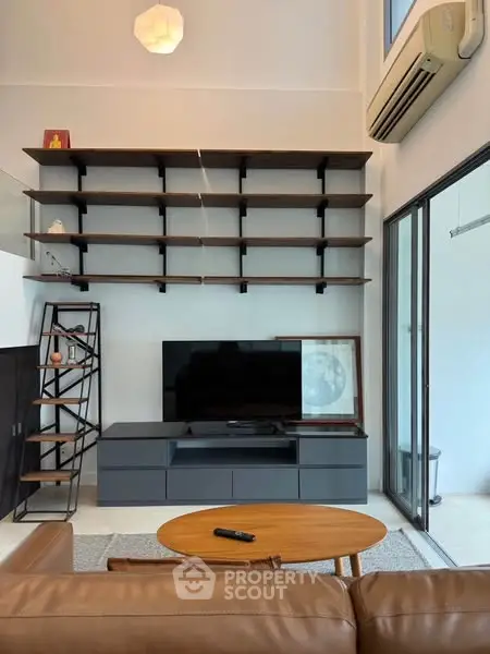 Modern living room with sleek shelving and TV unit, featuring a cozy leather sofa and stylish decor.