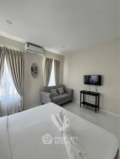Modern bedroom with air conditioning, cozy sofa, and wall-mounted TV, featuring elegant curtains and minimalist decor.