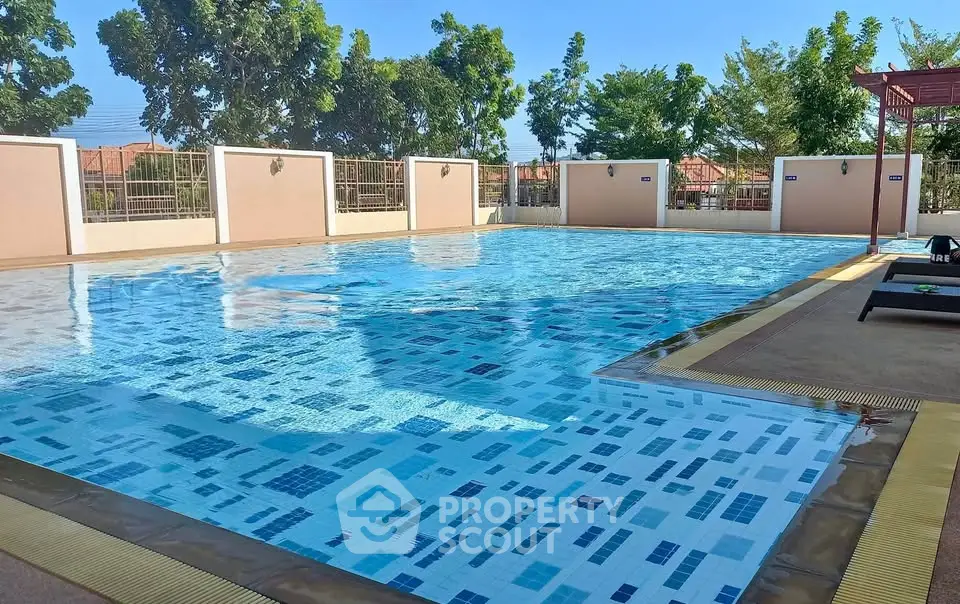 Luxurious outdoor swimming pool with clear blue water and surrounding greenery, perfect for relaxation.