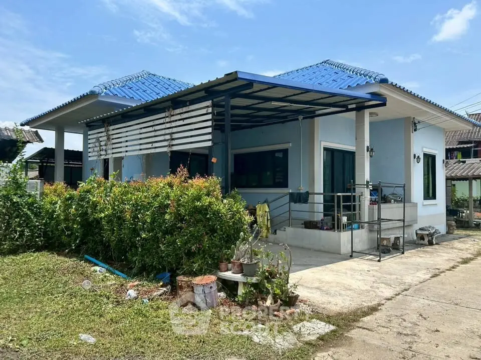 Charming single-story home with blue roof and lush garden, perfect for serene living.