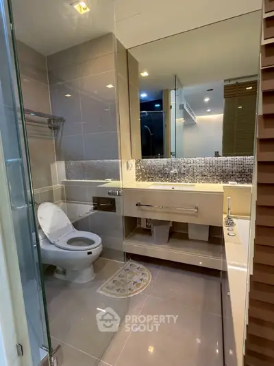 Modern bathroom with sleek fixtures and glass shower enclosure in a contemporary apartment.
