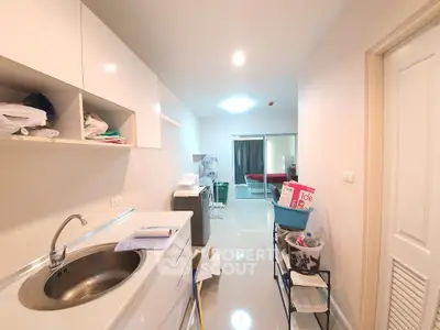 Modern kitchen with sleek cabinetry and stainless steel sink, leading to a bright living area with sliding glass doors.