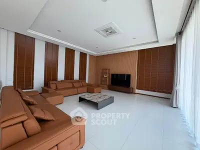Spacious modern living room with brown leather sofas and large windows