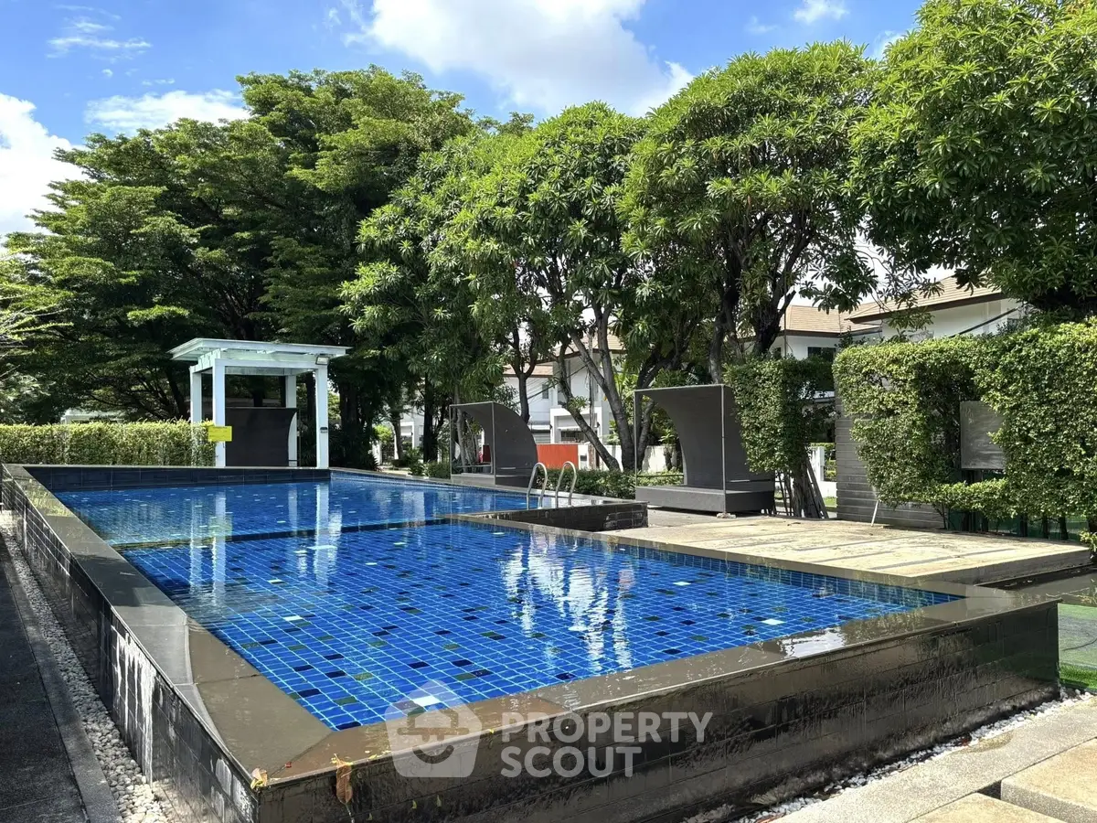 Luxurious outdoor pool surrounded by lush greenery in a serene residential area.