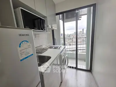 Modern compact kitchen with appliances and city view from balcony.