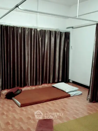 Spacious minimalist bedroom with large floor-to-ceiling curtains and ample natural light, perfect for a serene and peaceful living experience.