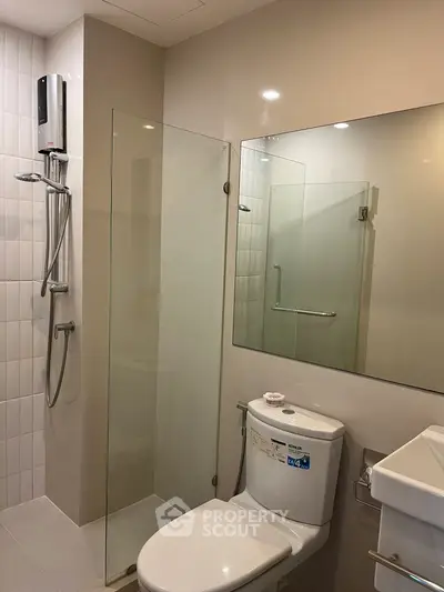 Modern bathroom with glass shower enclosure and sleek fixtures in a contemporary apartment.