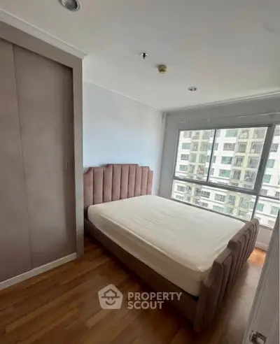 Modern bedroom with large window and built-in closet in urban apartment