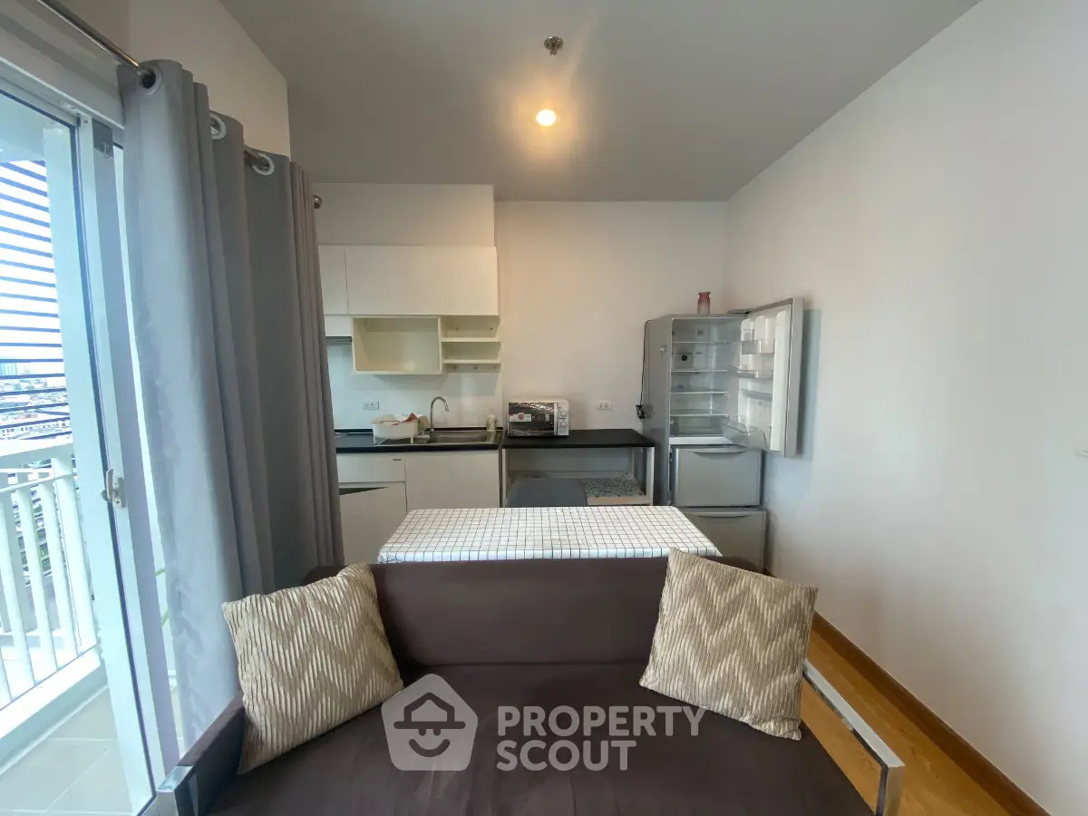 Modern apartment interior with open kitchen and cozy living area, featuring a balcony view.