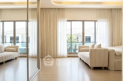 Spacious living room with elegant sofas and large windows offering abundant natural light.