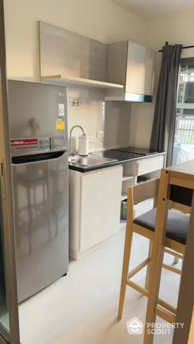 Modern kitchen with sleek cabinetry and stainless steel fridge in a bright apartment.