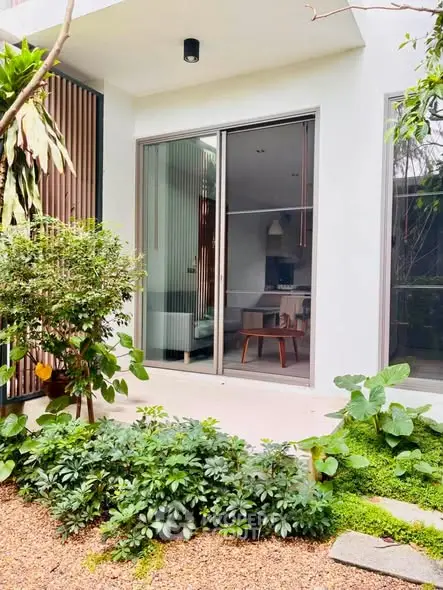 Charming garden view of modern home with sliding glass doors and lush greenery.