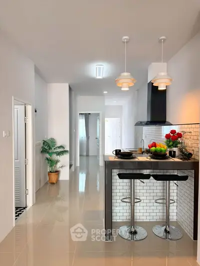 Modern kitchen with sleek breakfast bar and stylish lighting in a contemporary apartment.