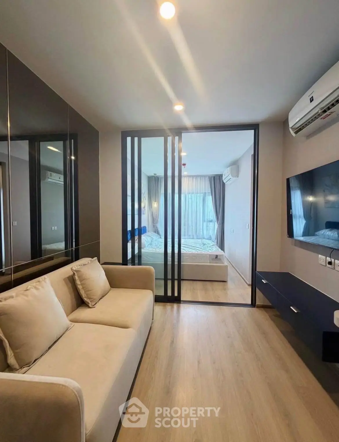 Modern living room with sliding glass doors leading to a stylish bedroom, featuring sleek furniture and natural light.