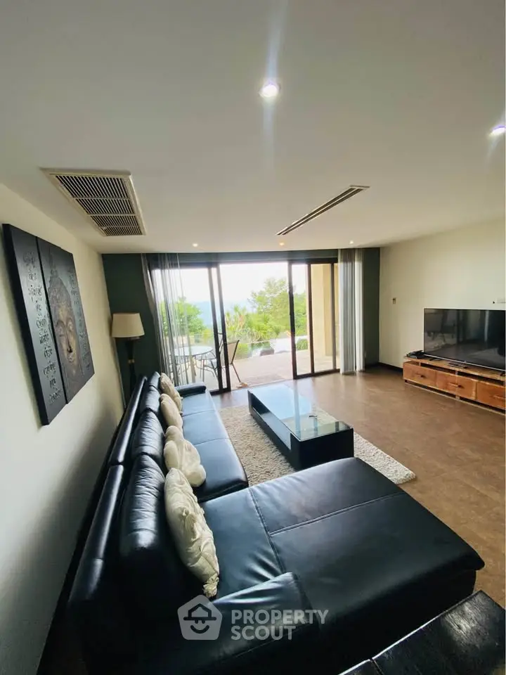 Spacious living room with modern decor and large windows offering a stunning view, perfect for relaxation.