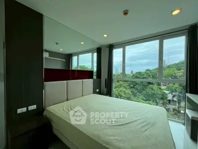 Modern bedroom with large windows offering lush green views and ample natural light.