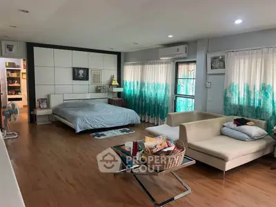 Spacious bedroom with modern decor and natural light, featuring a cozy seating area and stylish furnishings.