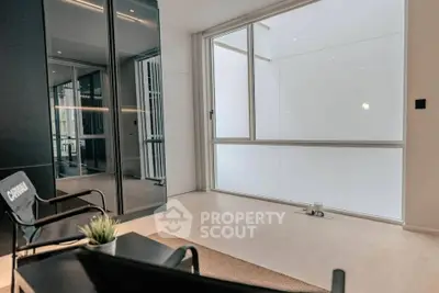 Modern minimalist living room with sleek black furniture and large frosted window