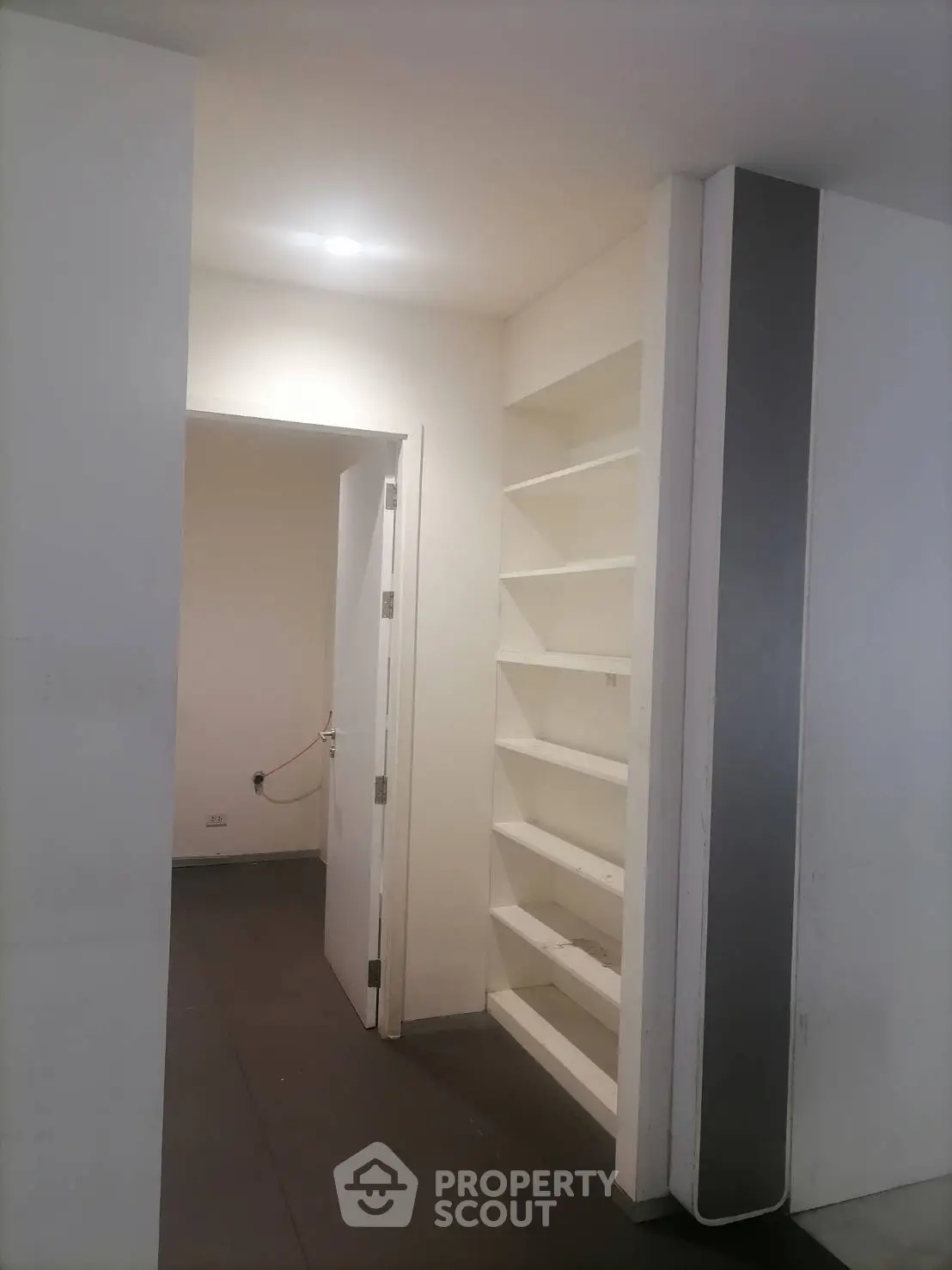 Modern interior with built-in shelving and open doorway, ideal for storage solutions.