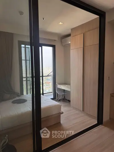 Modern bedroom with balcony view, featuring sleek wooden flooring and built-in wardrobe, perfect for urban living.