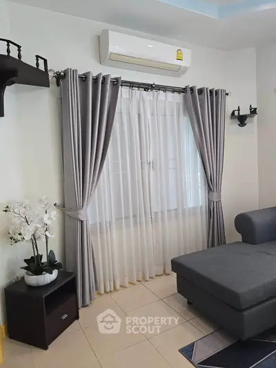 Stylish living room with modern grey sofa and elegant curtains, perfect for cozy relaxation.