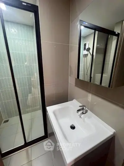 Modern bathroom with sleek shower and stylish sink in contemporary apartment.