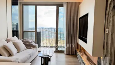 Modern living room with large windows and balcony offering stunning city views.