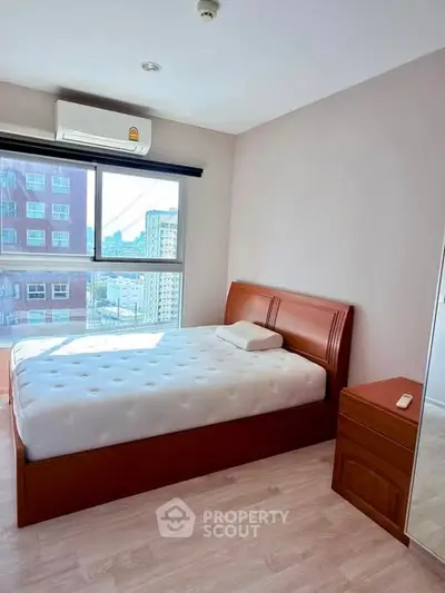 Bright bedroom with large window and wooden furniture in modern apartment