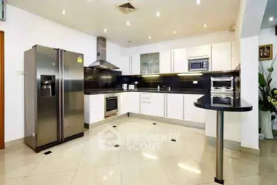 Modern kitchen with sleek appliances and open layout, featuring stainless steel fridge and ample counter space.