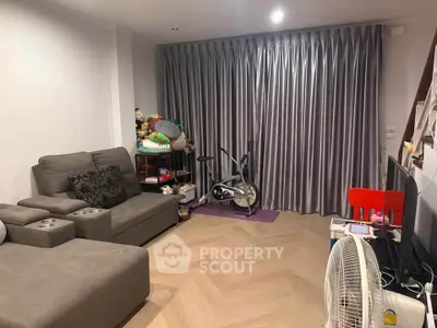 Cozy living room with modern furniture and exercise bike, perfect for relaxation and fitness.