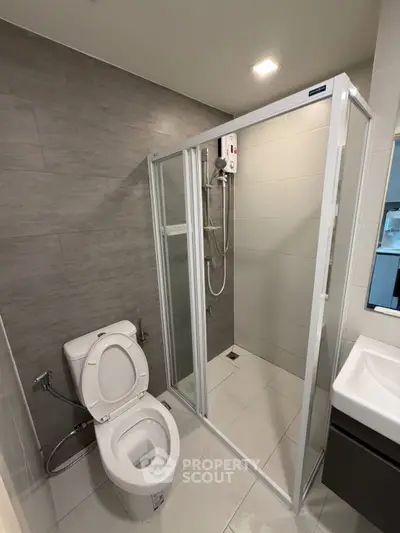 Modern bathroom with shower enclosure and sleek fixtures in contemporary apartment.