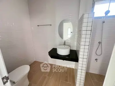 Modern bathroom with sleek fixtures and minimalist design, featuring a round mirror and stylish tile work.