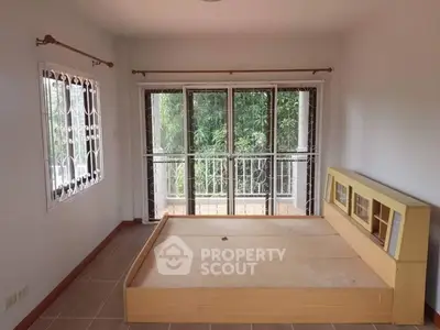 Spacious bedroom with large windows and balcony access, offering serene garden views.