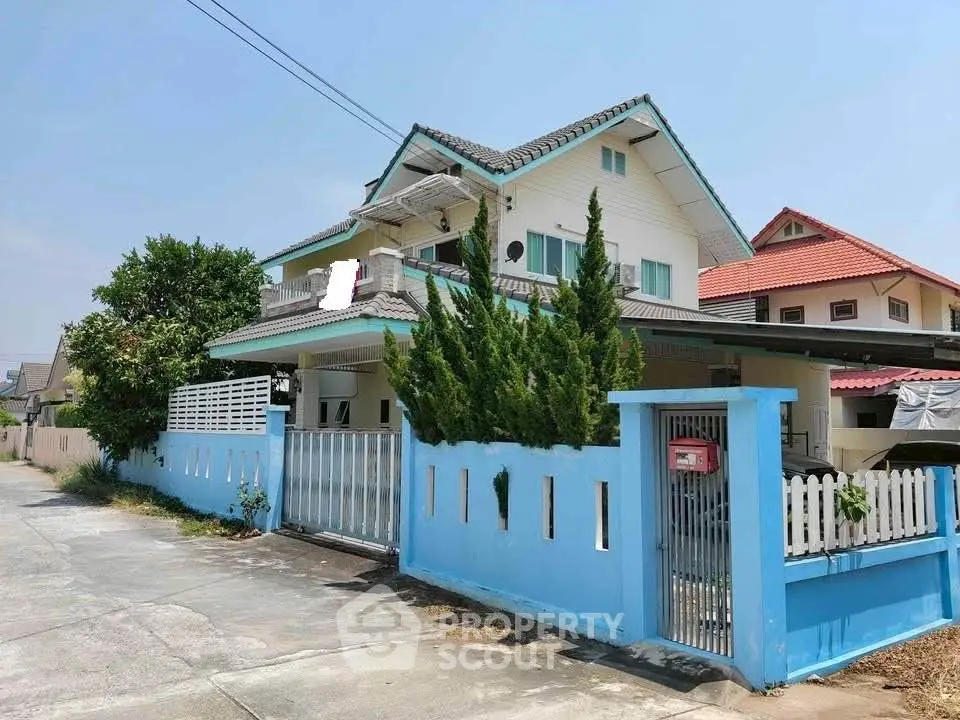 Charming two-story house with blue accents and lush greenery in a serene neighborhood.
