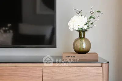 Elegant living room with modern TV and stylish decor vase on wooden cabinet.