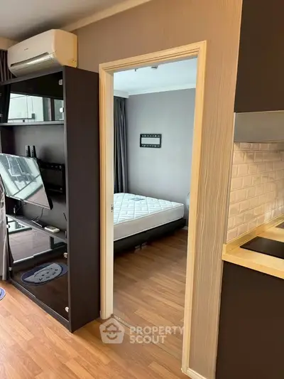 Modern apartment interior with bedroom and living area, featuring sleek design and wooden flooring.